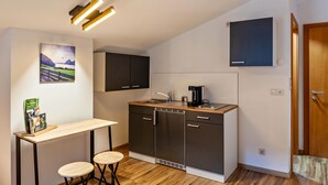 Une cuisine compacte équipée d’un lave-vaisselle intégré, d’une machine à café et d’un plan de travail en bois.
