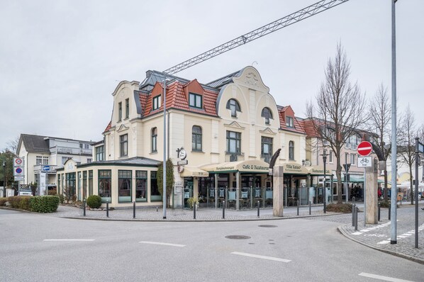 A multi-story building with a cafe and restaurant on the ground floor, a covered outdoor seating area, and a no entry sign. - Apartment 'Abendsonne' with Wi-Fi (Ostseebad Kühlungsborn)