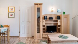 Ein Zimmer mit einem HolztV-Schrank, einem Tisch, einem Stuhl und einer Tür.