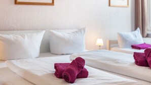 Ein Hotelzimmer mit zwei Betten, weißer Bettwäsche und violetten Handtüchern.