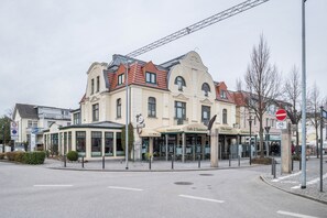 A multi-story building with a cafe and restaurant on the ground floor, a covered outdoor seating area, and a no entry sign. - Apartment 'Morgenröte' with Wi-Fi (Ostseebad Kühlungsborn)