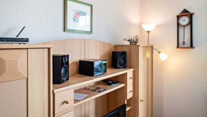 A room with a wooden desk, a clock, a framed picture, and a lamp. - Apartment 'Morgensonne' with Wi-Fi (Ostseebad Kühlungsborn)