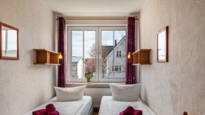 A room with two beds, a window with curtains, and wall-mounted shelves. - Apartment 'Kaiser' with Wi-Fi (Ostseebad Kühlungsborn)