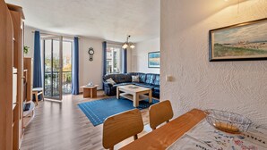 A modern living room with a sofa, a coffee table, and a dining area with chairs and a table. - Apartment 'Kaiser' with Wi-Fi (Ostseebad Kühlungsborn)