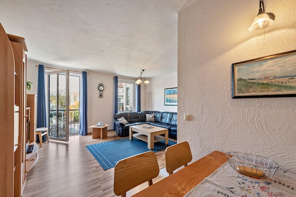 Uma sala de estar moderna com um sofá, uma mesa de centro e uma área de jantar com cadeiras e uma mesa.