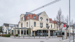 A multi-story building with a cafe and restaurant on the ground floor, a covered outdoor seating area, and a no entry sign. - Apartment 'Kaiser' with Wi-Fi (Ostseebad Kühlungsborn)