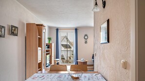 A dining area with a wooden table, chairs, a decorative bowl, a clock, and a view through a door. - Apartment 'Kaiser' with Wi-Fi (Ostseebad Kühlungsborn)