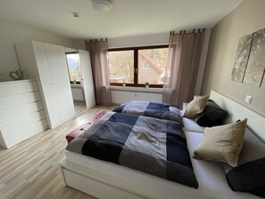 Une chambre à coucher avec un lit, une armoire, une fenêtre avec des rideaux et un radiateur.