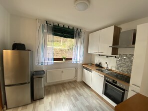 Une cuisine de taille réduite, équipée d’un réfrigérateur, d’une cuisinière, d’un évier et d’une fenêtre avec des rideaux.