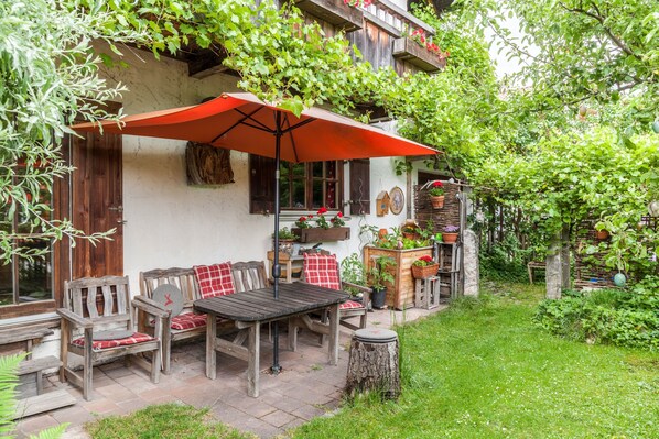 Une terrasse extérieure avec des meubles en bois, un parasol rouge et des plantes en pot.