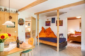 Une pièce comprenant un lit, une table à manger avec des chaises, un meuble en bois et un miroir.