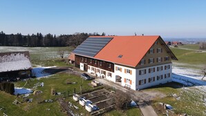 A large building with a red roof, solar panels, and a small garden area.