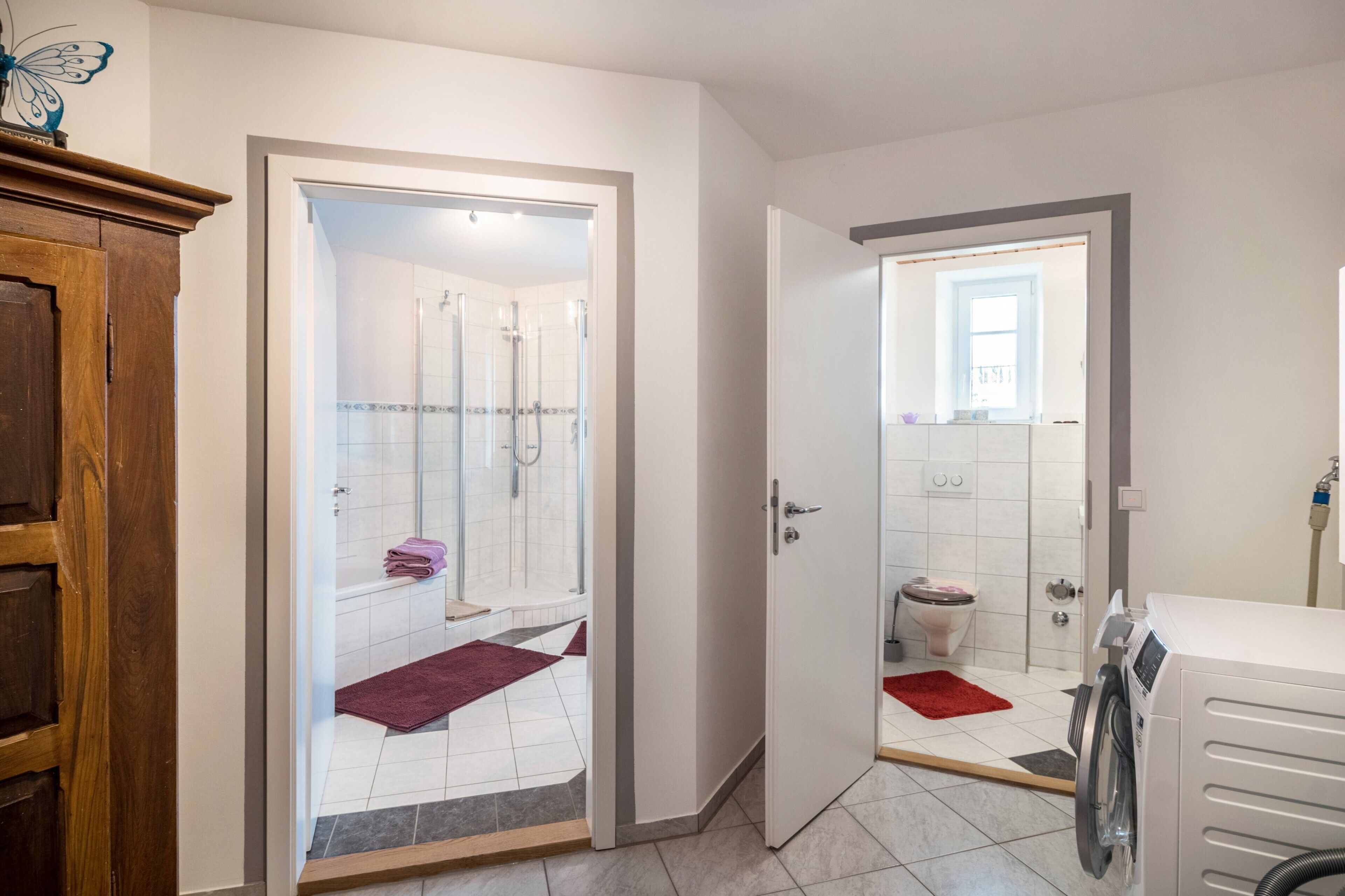 A bathroom with a shower, toilet, and a washing machine.