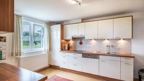 A modern kitchen with white cabinets, a wooden countertop, and a window with curtains.