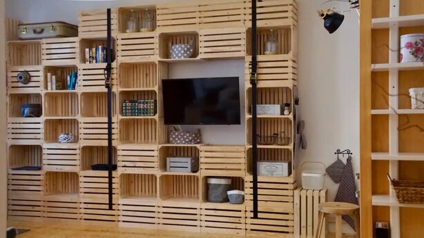 A room with a built-in wooden shelving unit, a flat-screen TV, and various storage boxes. - Chalet 'Feinis' with Private Terrace, Garden, and Wi-Fi (Waasen)