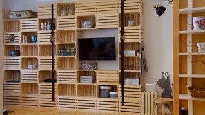 A room with a built-in wooden shelving unit, a flat-screen TV, and various storage boxes. - Chalet 'Feinis' with Private Terrace, Garden, and Wi-Fi (Waasen)