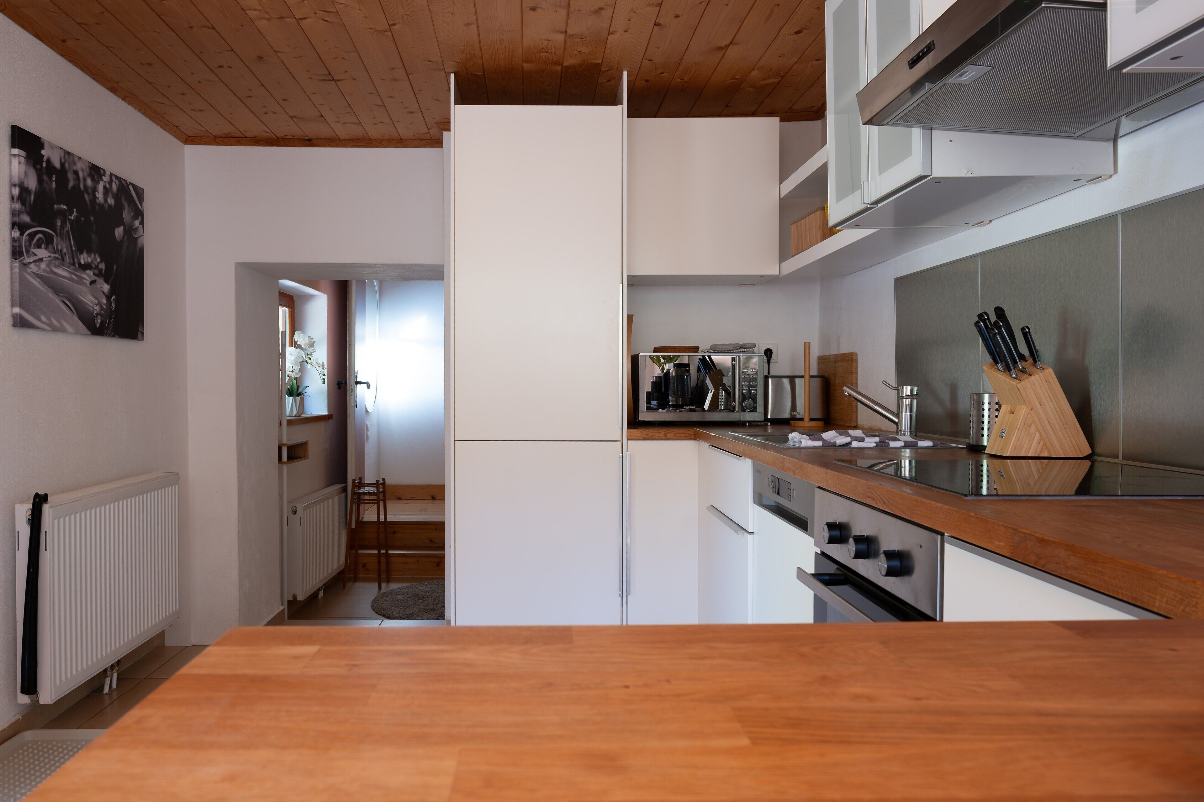 A modern kitchen with white cabinetry, a wooden countertop, and stainless steel appliances.