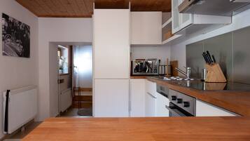 A modern kitchen with white cabinetry, a wooden countertop, and stainless steel appliances.