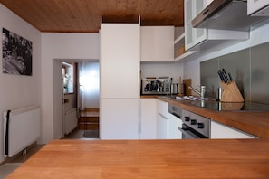 A modern kitchen with white cabinetry, a wooden countertop, and stainless steel appliances.