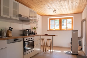 A modern kitchen with wooden cabinets, a built-in oven, a coffee maker, and a window with a view of the outdoors.