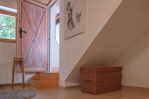 Ein Zimmer mit Holztür, einem Korbwannen und einem gerahmten Kunstwerk an der Wand.