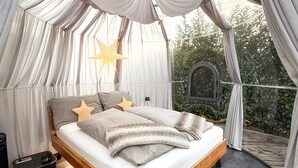 Un dormitori amb llit amb dosser, decoració d'estels i vista a vegetació a l'exterior.
