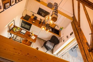 A modern kitchen with wooden beams, a dining area with a wooden table, and a view of the living room below. - Chalet 'Sternenzauber' with Private Terrace and Wi-Fi (Waasen)