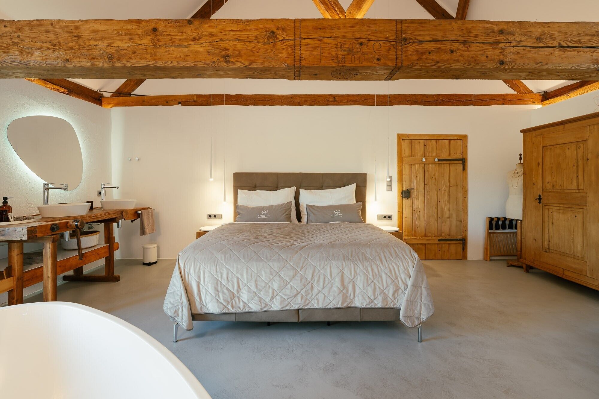 Un dormitorio con una cama grande, vigas de madera, un armario de madera y un espejo redondo.