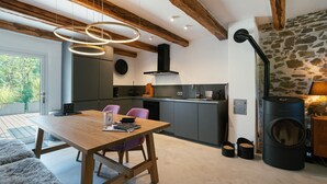 Een moderne keuken met een stenen muur, een ingebouwde kookplaat en een eethoek met een houten tafel en stoelen.