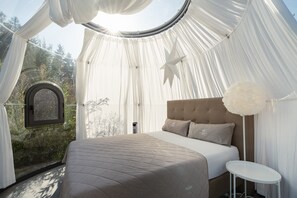 Ein Schlafzimmer mit einem Bett, einem runden Tisch und einem Fenster mit Vorhängen.