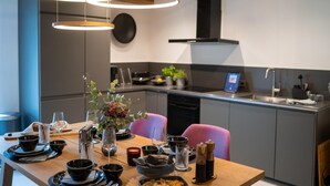 Een moderne keuken met een eethoek, met een houten tafel gedekt voor een maaltijd, een inbouwoven en een zwarte afzuigkap.
