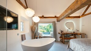 Een moderne badkamer met een vrijstaand bad, een houten wastafelmeubel en een grote spiegel.