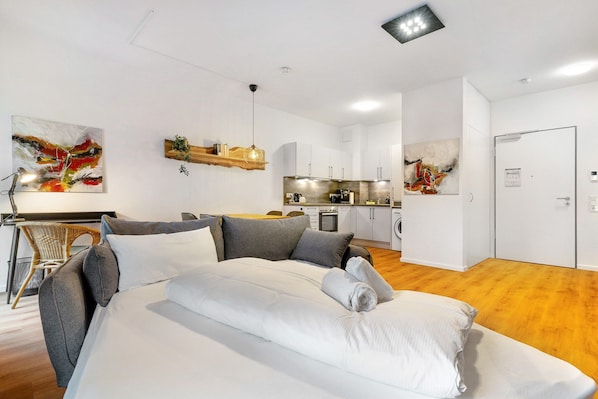 Ein modernes Hotelzimmer mit Bett, Schreibtisch und einer Küchenzeile.