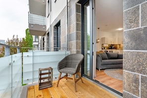 Ein Balkon mit Korbmöbeln, einem kleinen Tisch und einem Glasgeländer.
