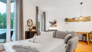 Una habitación de hotel moderna con una cama grande, un sofá, un escritorio y vistas al exterior.