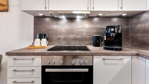 Una cocina moderna con estufa, horno y cafetera integrados.