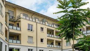 A multi-story residential building with balconies, a tree in the foreground, and a clear sky. - Studio Apartment 'Km Style  Nr 1' with Private Terrace and Wi-Fi (Freiburg im Breisgau)