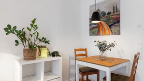 A dining area with a wooden table, chairs, a hanging pendant light, and a wall-mounted painting. - Studio Apartment 'Km Style  Nr 1' with Private Terrace and Wi-Fi (Freiburg im Breisgau)