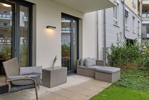 A patio with wicker furniture, a glass door, and a view of a building.