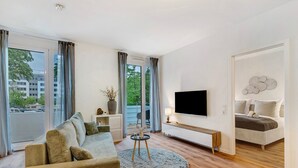 A modern living room with a sofa, TV, and a bed.