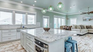 A spacious kitchen with a large island, white cabinetry, and a dining area with a sofa and chairs.