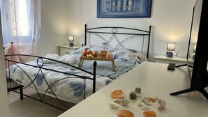 A bedroom with a bed, bedside tables, a desk, and a wall-mounted artwork.