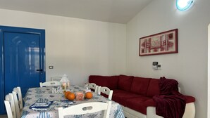 A dining area with a table set for two, a red sofa, and a blue door.