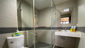 A bathroom with a toilet, a glass-enclosed shower, and a sink with toiletries. - Friend Homestay (Toucheng)