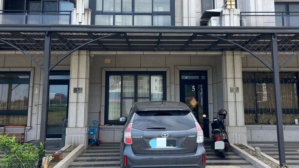 A modern building with a grey facade, large windows, and a covered entrance. A car is parked in front, and a motorcycle is visible to the right. - Friend Homestay (Toucheng)