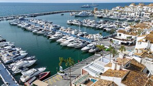 A marina with numerous boats docked, a pier extending into the water, and buildings with traditional architecture. - 243-Fully Renovated-Puerto Banus Marbella Front Line Penthouse (Marbella)