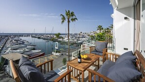 A balcony with a view of a marina, wooden furniture, and a bottle of wine. - 243-Fully Renovated-Puerto Banus Marbella Front Line Penthouse (Marbella)
