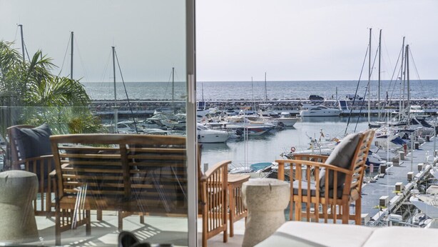 A view from a balcony overlooking a marina with boats, wooden chairs, and a table with books. - 243-Fully Renovated-Puerto Banus Marbella Front Line Penthouse (Marbella)