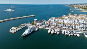 A marina with several yachts docked, a large cruise ship in the background, and a coastal town with white buildings. - 243-Fully Renovated-Puerto Banus Marbella Front Line Penthouse (Marbella)