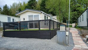 A residential area with a fenced yard, a pathway, and a house with a garage. - The Shak, Tarbolton, Middlemuir Holiday Park (Tarbolton  Mauchline)